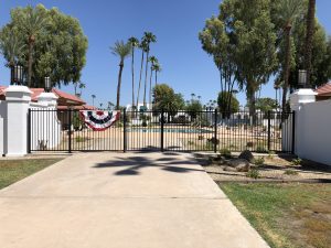 A black wrought iron pool gate secures a community's pool area.