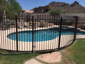 Black wrought iron fence surrounds a residential pool area.