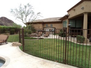 Brown wrought iron fence secures a residential swimming pool.