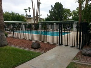 Black wrought iron fence and gate secures pool area at apartment complex.