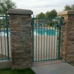 Turquoise-colored wrought iron pool fence and gate secure a community pool area.