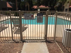 Wrought iron pool gate with pool safety guidelines secures a community pool area.