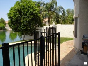 Black wrought iron fence secures a residential pool area.