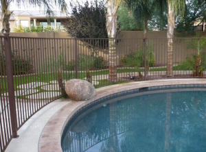 A wrought iron pool fence encloses a residential pool area.