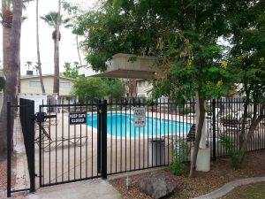 A wrought iron fence and gate secure a community pool area.